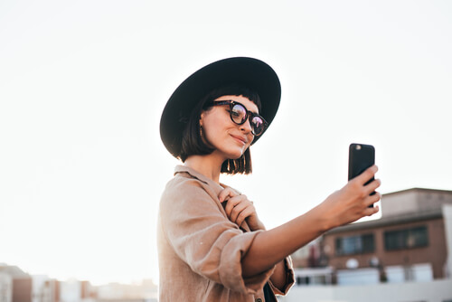 A girl wearing a hat and holding a phone