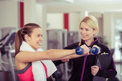 A women personal trainer guiding another women holding a dumbell - best gyms in nottingham